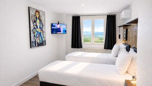 Habitación de hotel con dos camas, un televisor, un cuadro y una ventana con vistas.