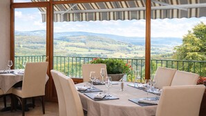 Un comedor con mesas dispuestas para dos, con vistas a un paisaje pintoresco.