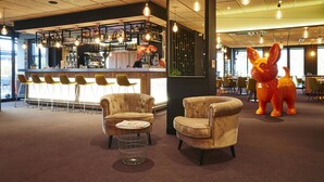 A bar area with a counter, bar stools, and a large decorative animal sculpture. - Kyriad Clermont Ferrand Nord - Riom (Riom)