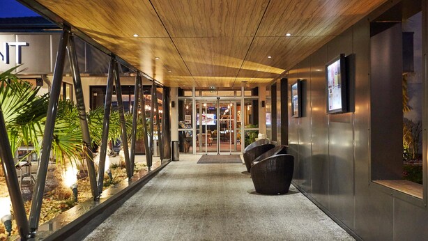 A modern hotel entrance with a wooden ceiling, glass doors, and a pathway leading to the lobby. - Kyriad Clermont Ferrand Nord - Riom (Riom)
