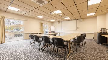 A conference room with a long table, black chairs, a projector, and a whiteboard.