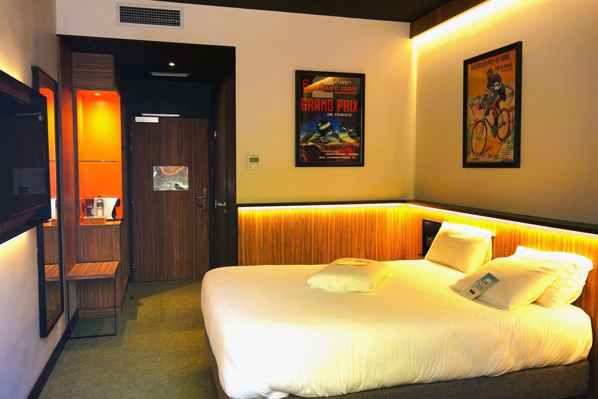 Habitación de hotel con cama, escritorio y una silla. Hay carteles en la pared.