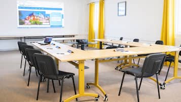 Une salle de conférence équipée d’une grande table, de chaises, d’un ordinateur portable et d’un écran de présentation.