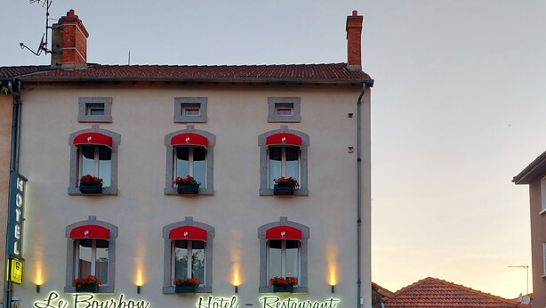Un hotel con un letrero que dice "Le Bourbon Hotel - Restaurant" y mesas al aire libre.