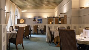 Un área de comedor con mesas dispuestas para el servicio, sillas y un atril para el menú.