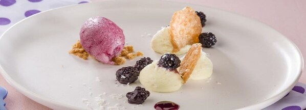 Un plato de postre con helado y frutos rojos.