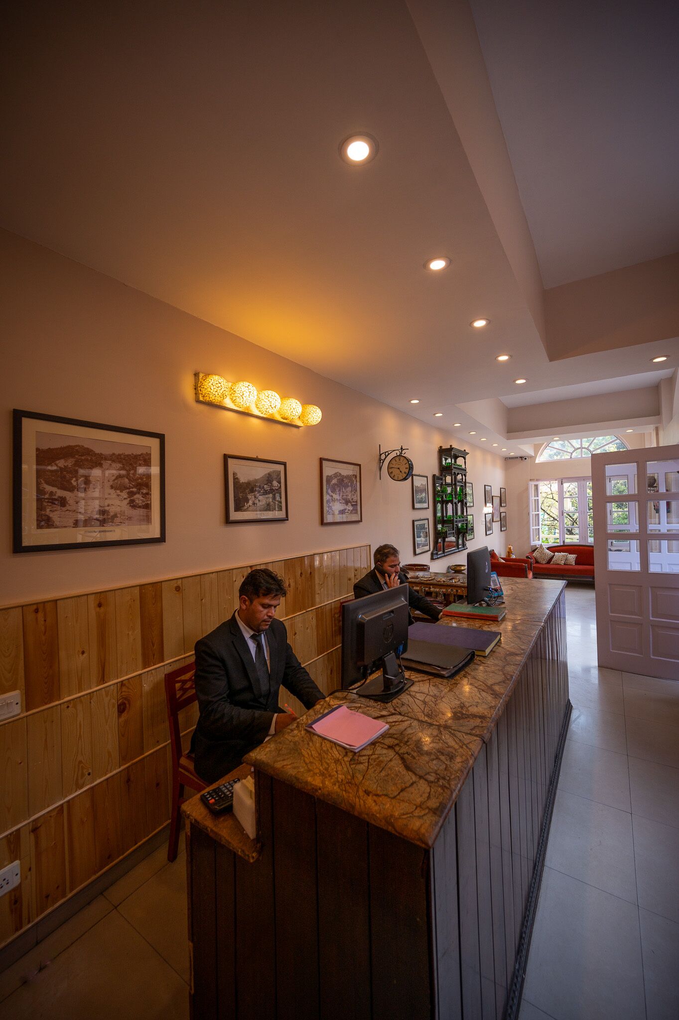 A reception area with wooden paneling, a marble counter, and framed pictures on the wall.