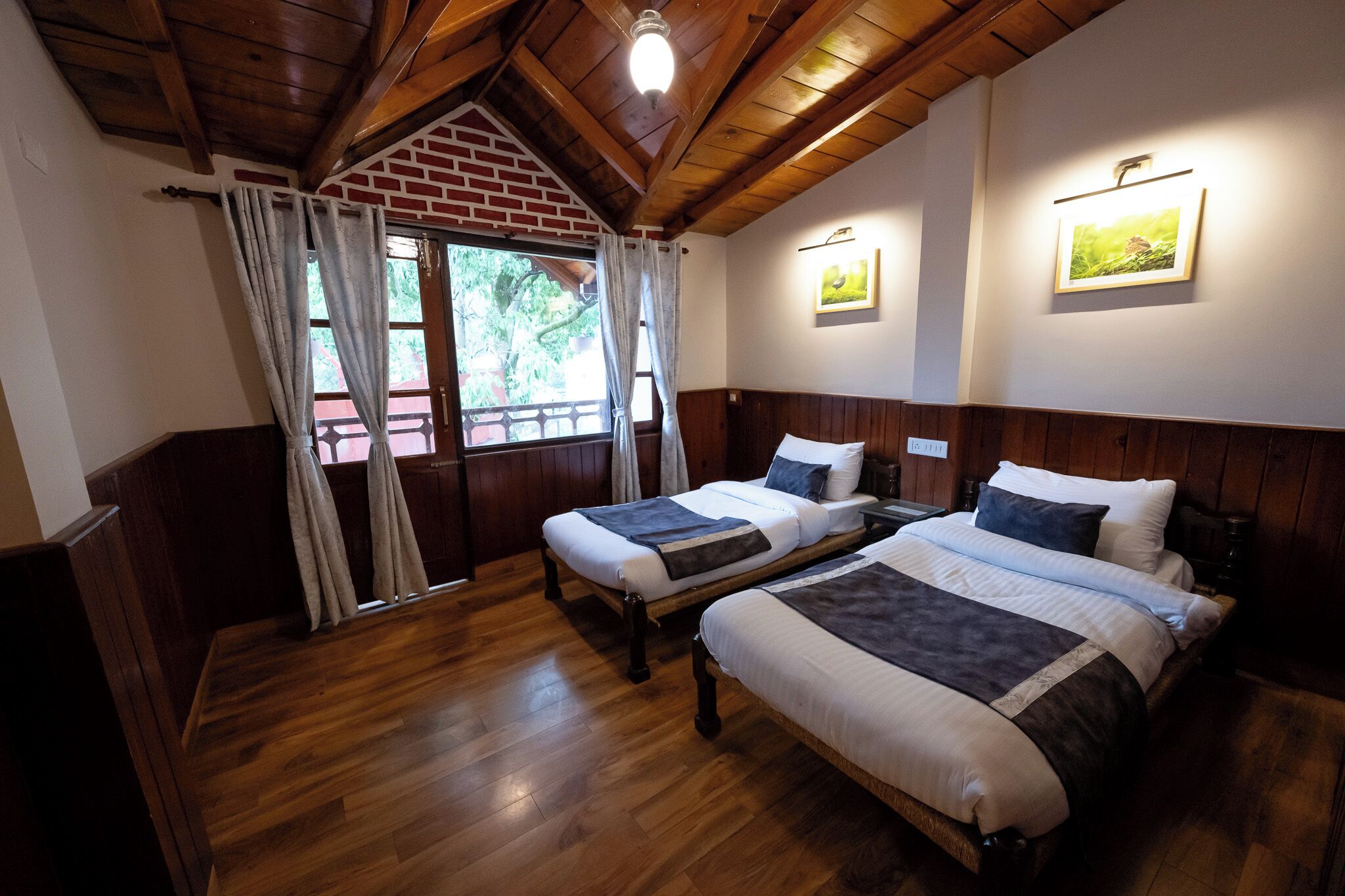 Una habitación con dos camas de madera, una pared de ladrillo y una ventana con cortinas.