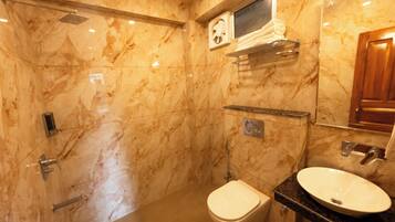 A bathroom with marble walls, a toilet, a bidet, a sink, and a mirror.