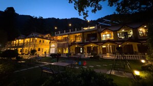 A multi-story hotel with outdoor seating and a well-lit entrance.