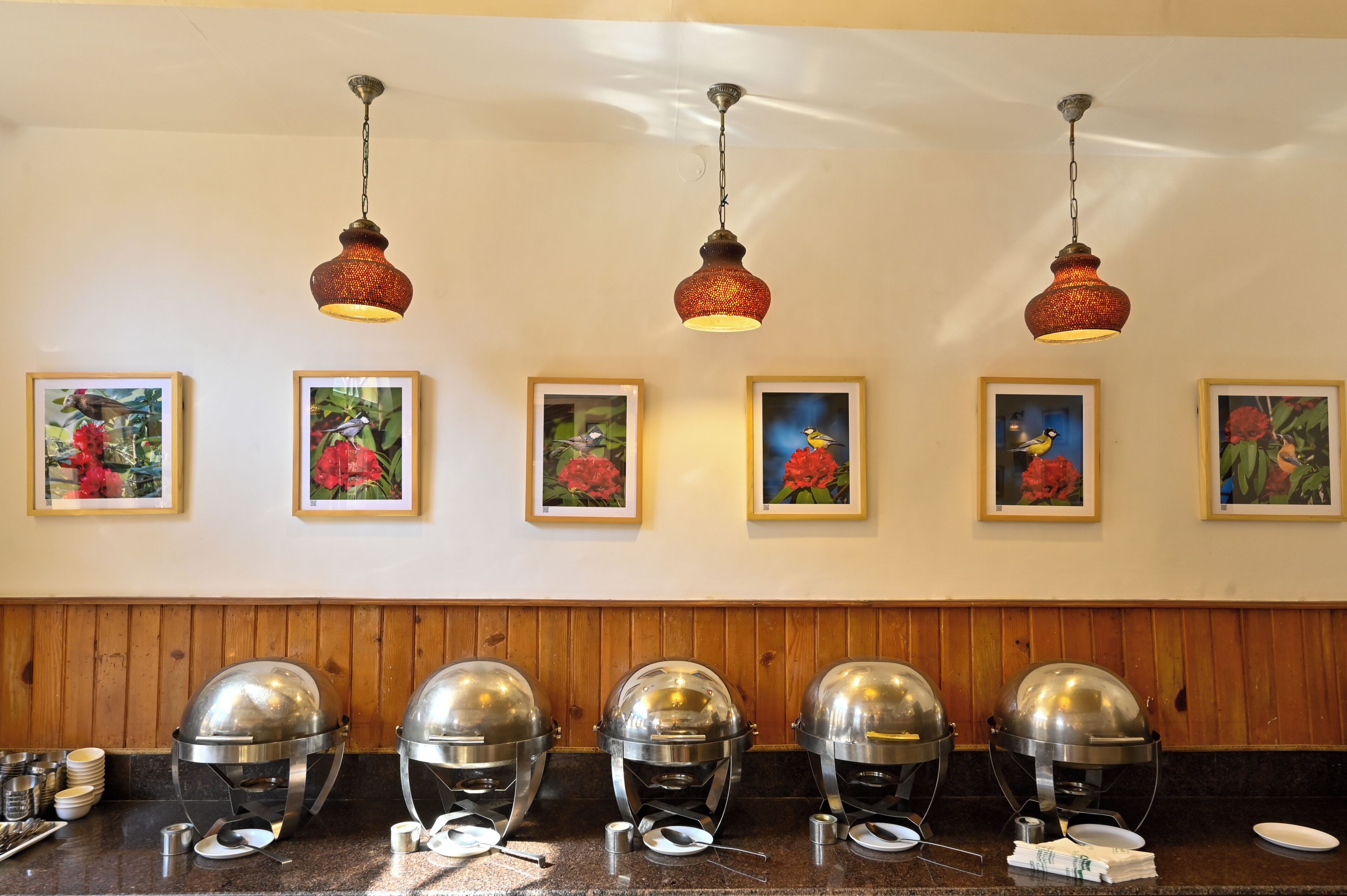 Ein Buffet mit mehreren Speiseausgaben, Blumenbilder an der Wand und Holzvertäfelung.