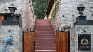 A stone staircase leading to a gated entrance with a bird sculpture and a sign reading "The Pavilion".