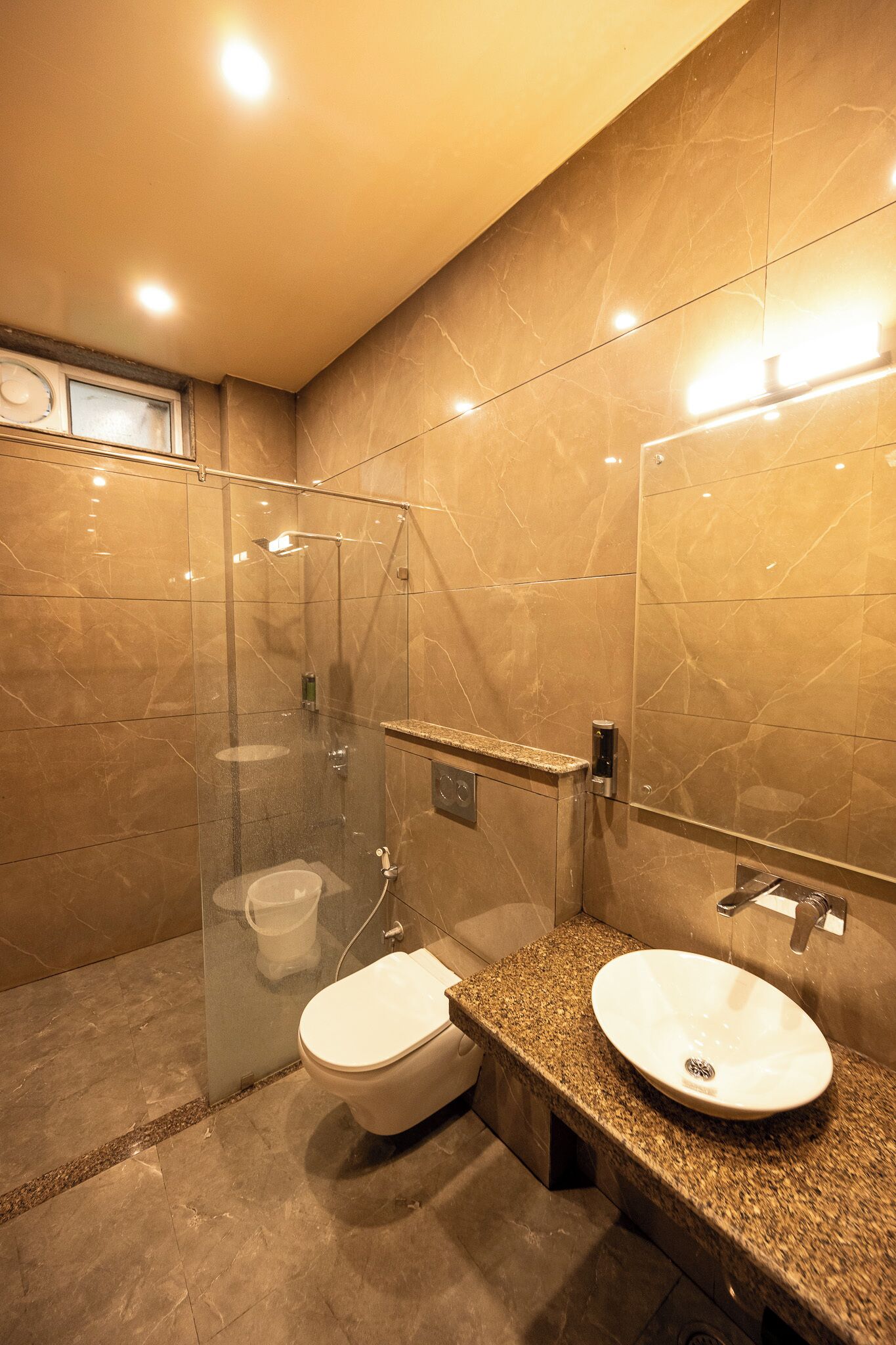Un baño moderno con ducha envuelta en cristal, tocador doble y retrete.