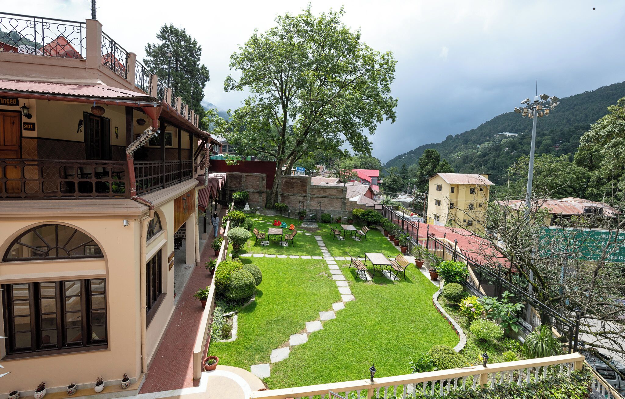 A courtyard with a lawn, seating area, and a view of surrounding buildings and hills.