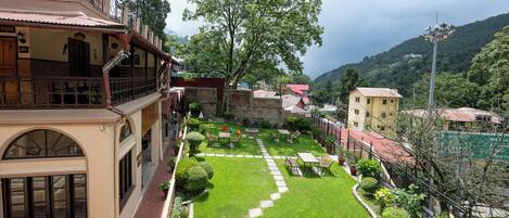 A courtyard with a lawn, seating area, and a view of surrounding buildings and hills.