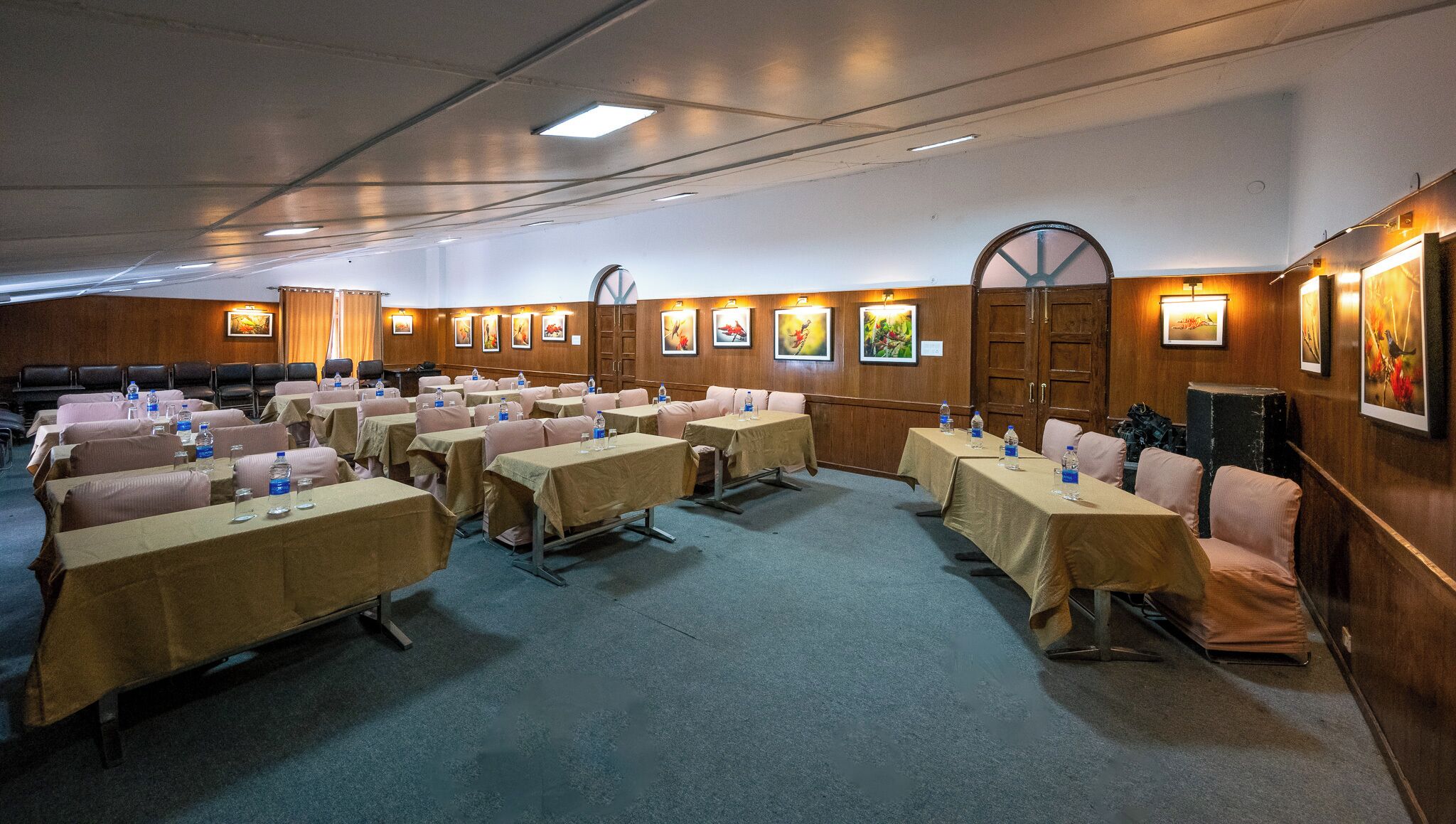 A conference room with tables and chairs, water bottles, and framed pictures on the walls.