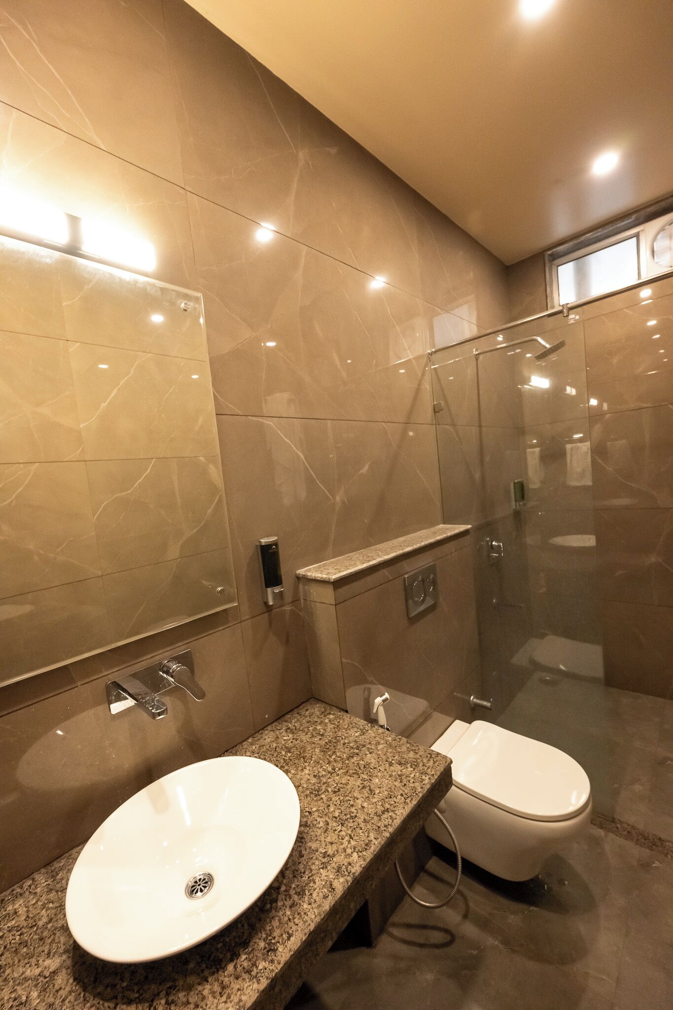 A modern bathroom with a granite countertop, a white sink, and a glass-enclosed shower.
