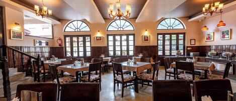 A restaurant with multiple dining tables, chairs, and chandeliers.
