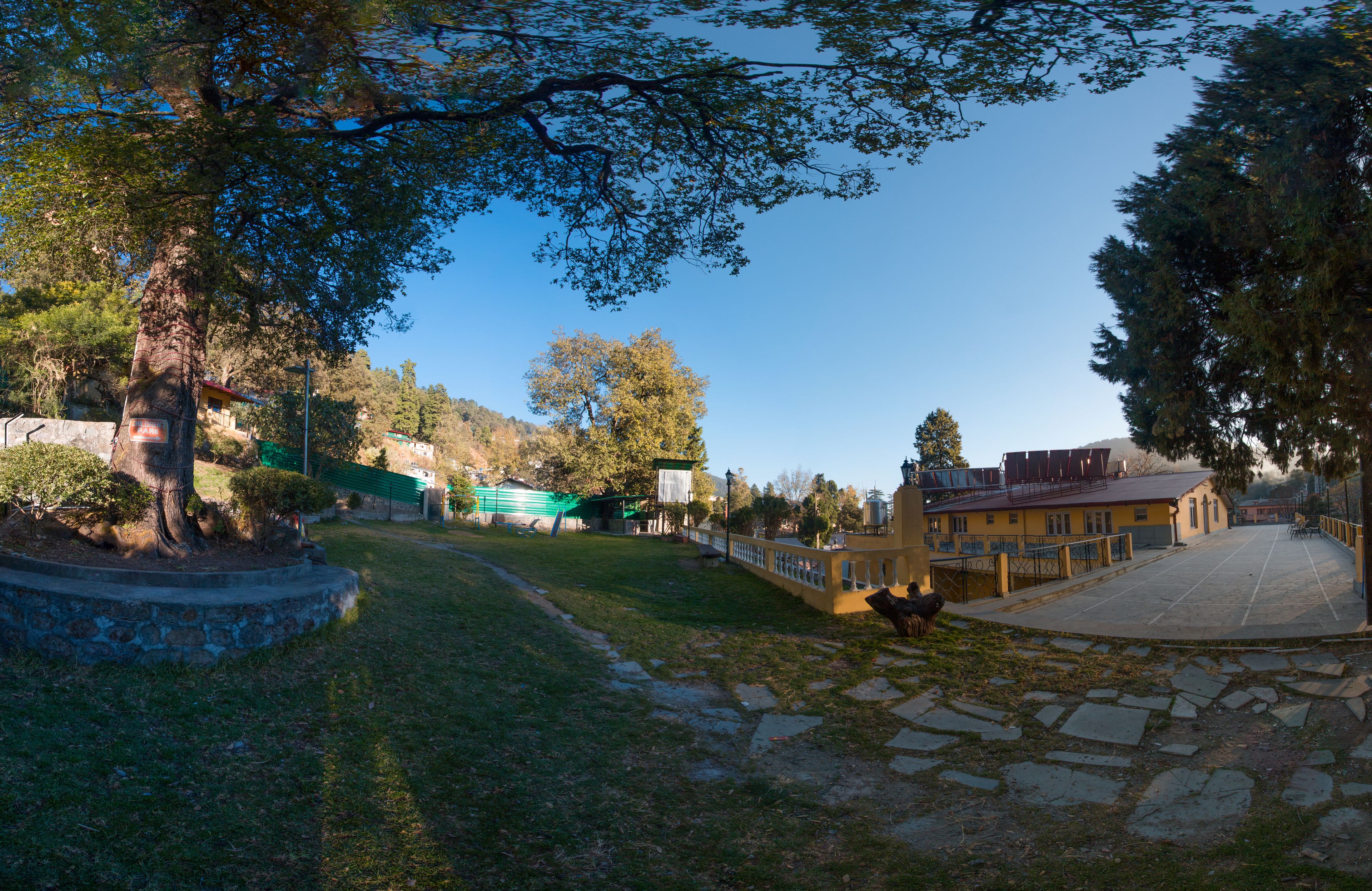 A courtyard with a stone pathway, a small garden area, and a building with a yellow facade.