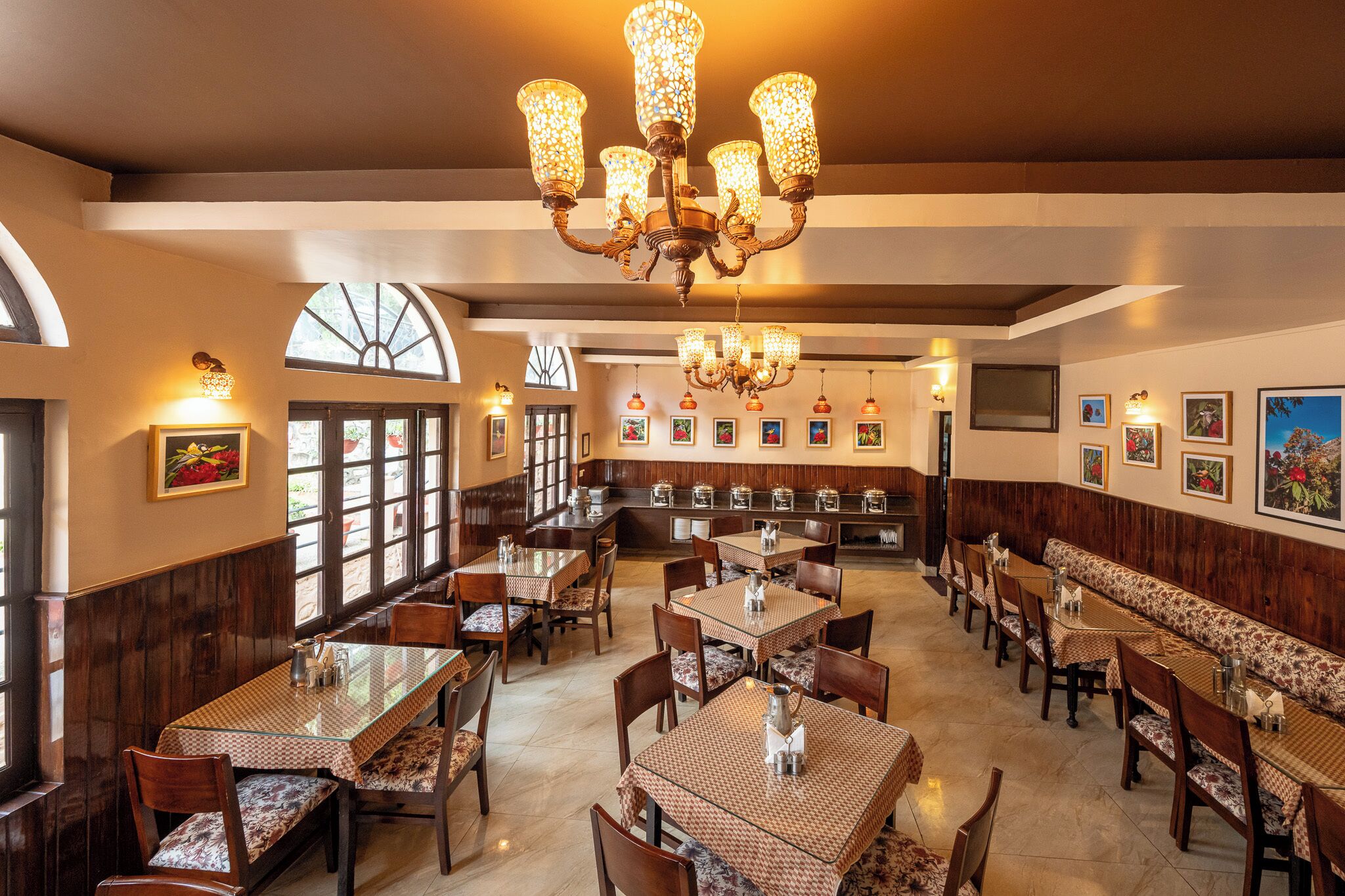 A restaurant with multiple dining tables and booths, a chandelier, and framed artwork on the walls.