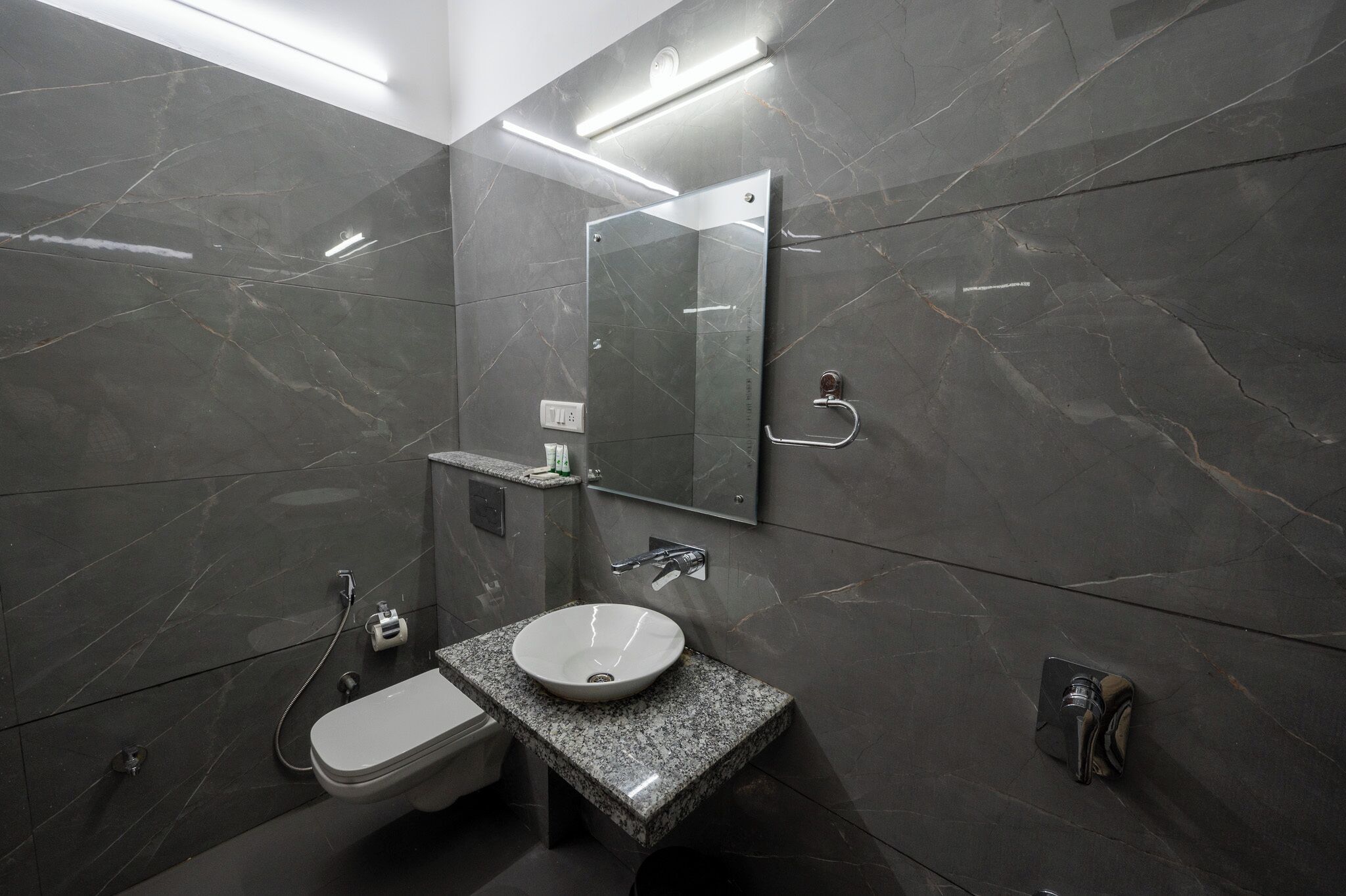 Un baño moderno con tocador de mármol, inodoro y cabina de ducha de vidrio.