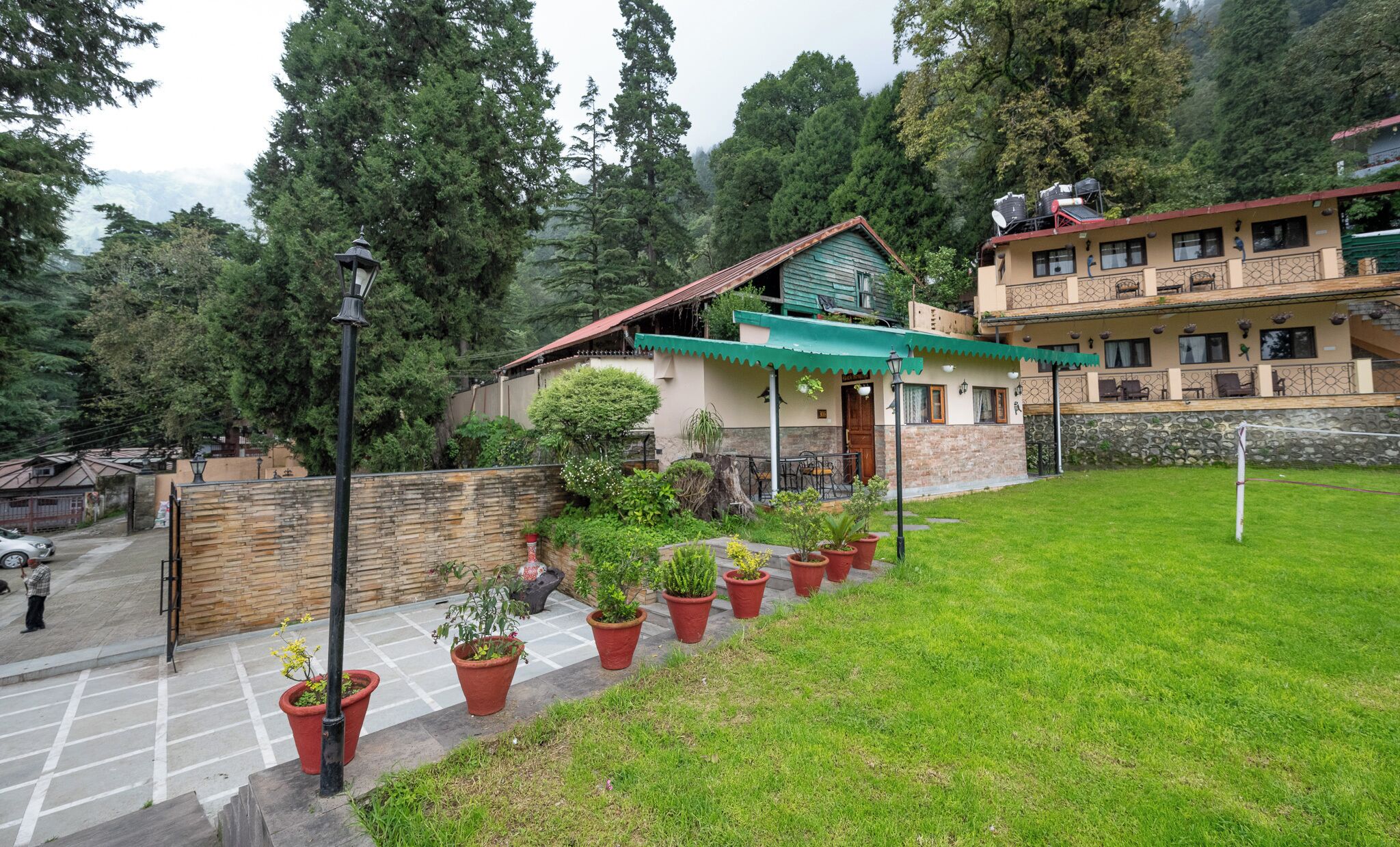 A hotel with a green roof, a stone wall, and potted plants in the foreground.