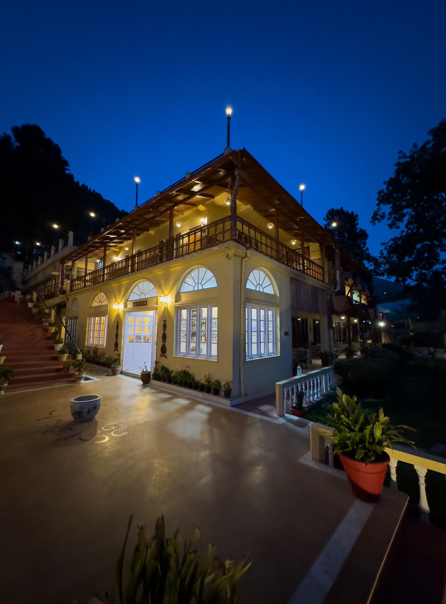 A two-story building with a balcony, arched windows, and a well-lit entrance.