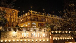 A building with a sign reading "THE PAVILION" at night, surrounded by trees and illuminated by string lights.
