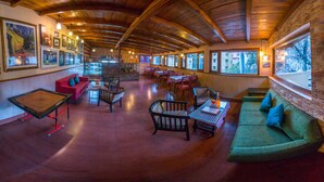 A spacious interior with wooden ceilings, multiple seating areas, and large windows offering views of the outside.