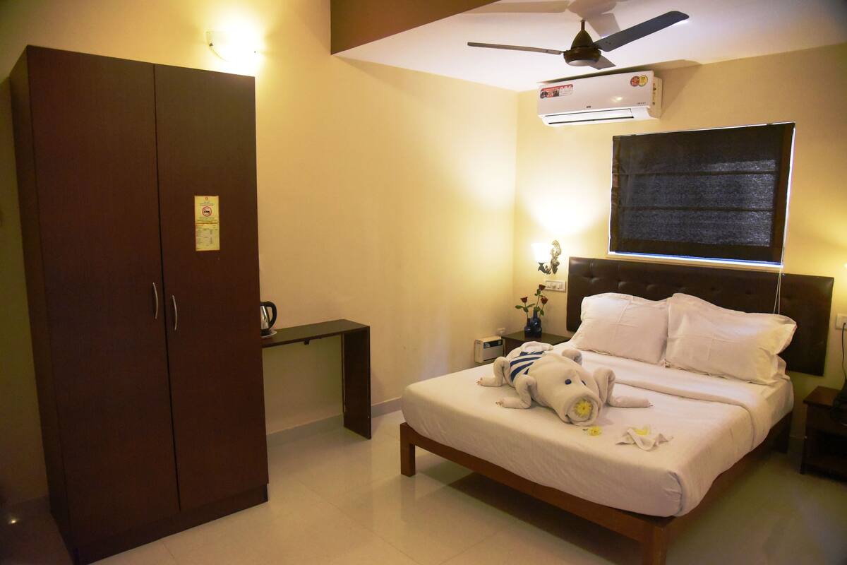 Un dormitorio con cama, armario, escritorio y ventilador de techo.