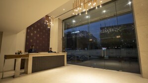 A reception area with a reception desk, a large glass window, and a modern light fixture.