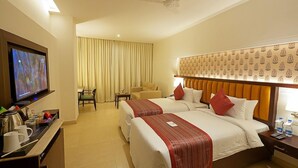 A hotel room with two beds, a television, a desk with a coffee maker, and a chair.
