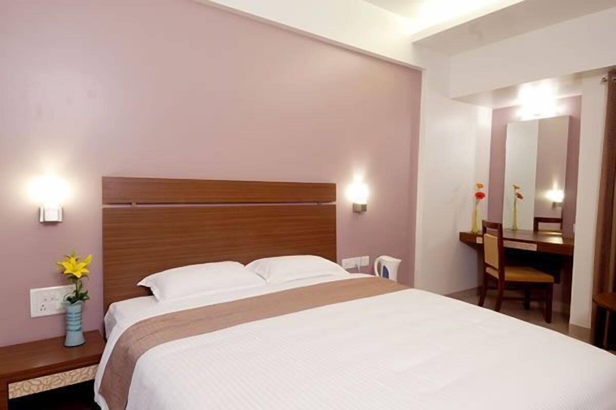 A hotel room with a bed, bedside table, lamp, and a mirror.