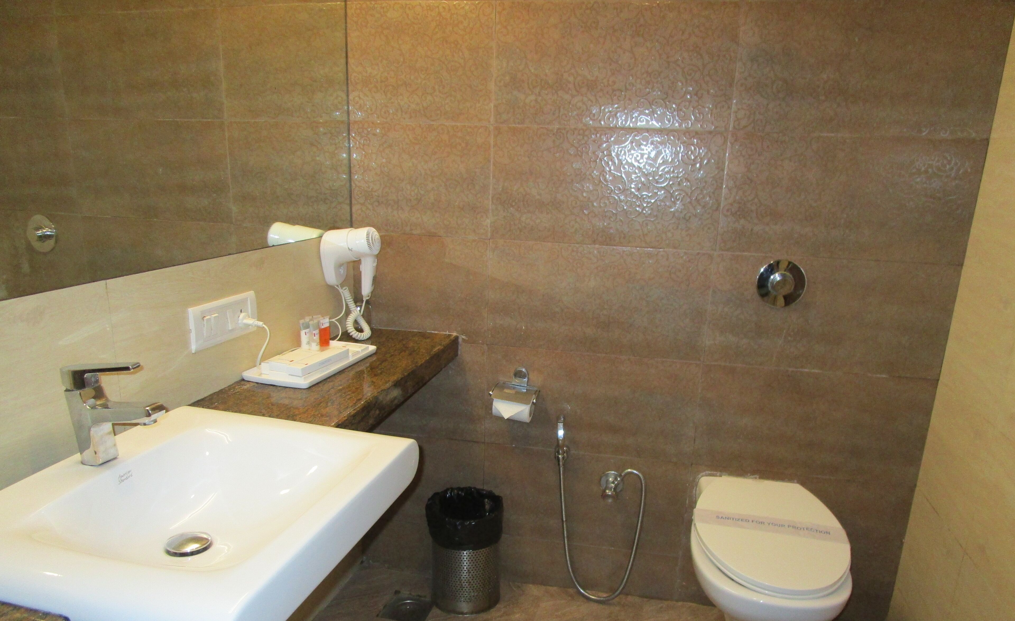 A bathroom with a sink, a hairdryer, a toilet, and a shower.