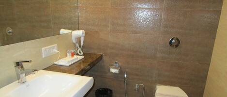 A bathroom with a sink, a hairdryer, a toilet, and a shower.
