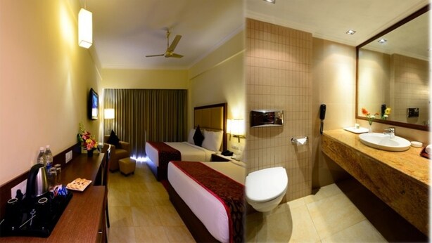 A hotel room with a bed, bedside table, and a bathroom with a sink and toilet. - The Chariot Resort & Spa (Puri)