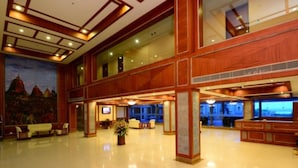 A spacious lobby with a high ceiling, wooden paneling, and a large mural on the wall. - The Chariot Resort & Spa (Puri)