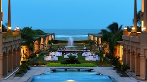 An outdoor wedding setup with a pool, tables, and chairs arranged for guests, overlooking the ocean. - The Chariot Resort & Spa (Puri)