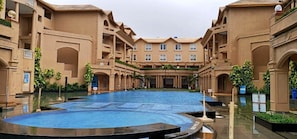 A hotel courtyard with a central pool, multiple balconies, and lush greenery. - The Chariot Resort & Spa (Puri)
