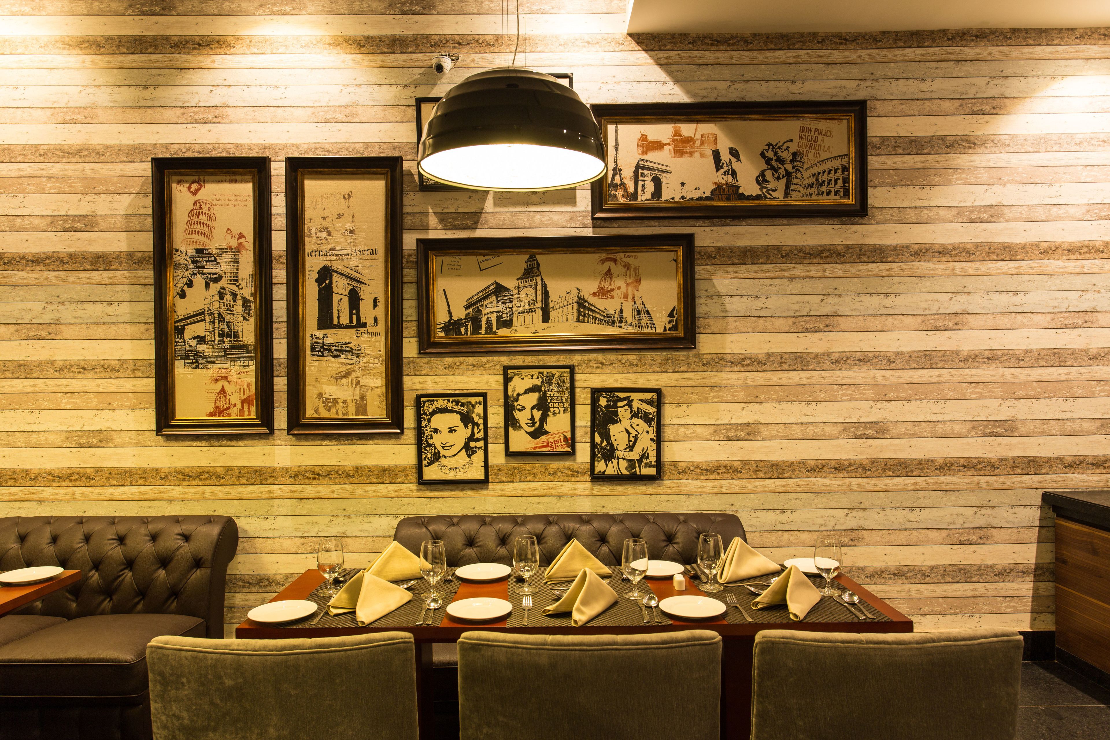 Un comedor con pared de madera, cuadros enmarcados y una mesa dispuesta para cuatro.