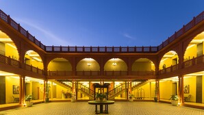 A spacious courtyard with a central round table, multiple arches, and a staircase leading to an upper level.