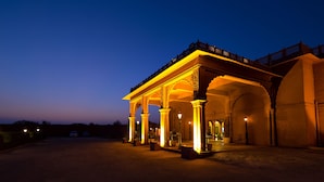 A building with a covered entrance, columns, and a balcony with railings.