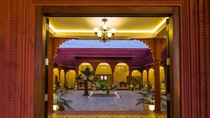 An ornate lobby with a central fountain, arched columns, and a chandelier.