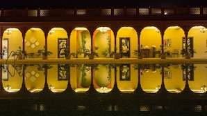 A hotel facade with multiple arched doorways, each with a small balcony and potted plants.