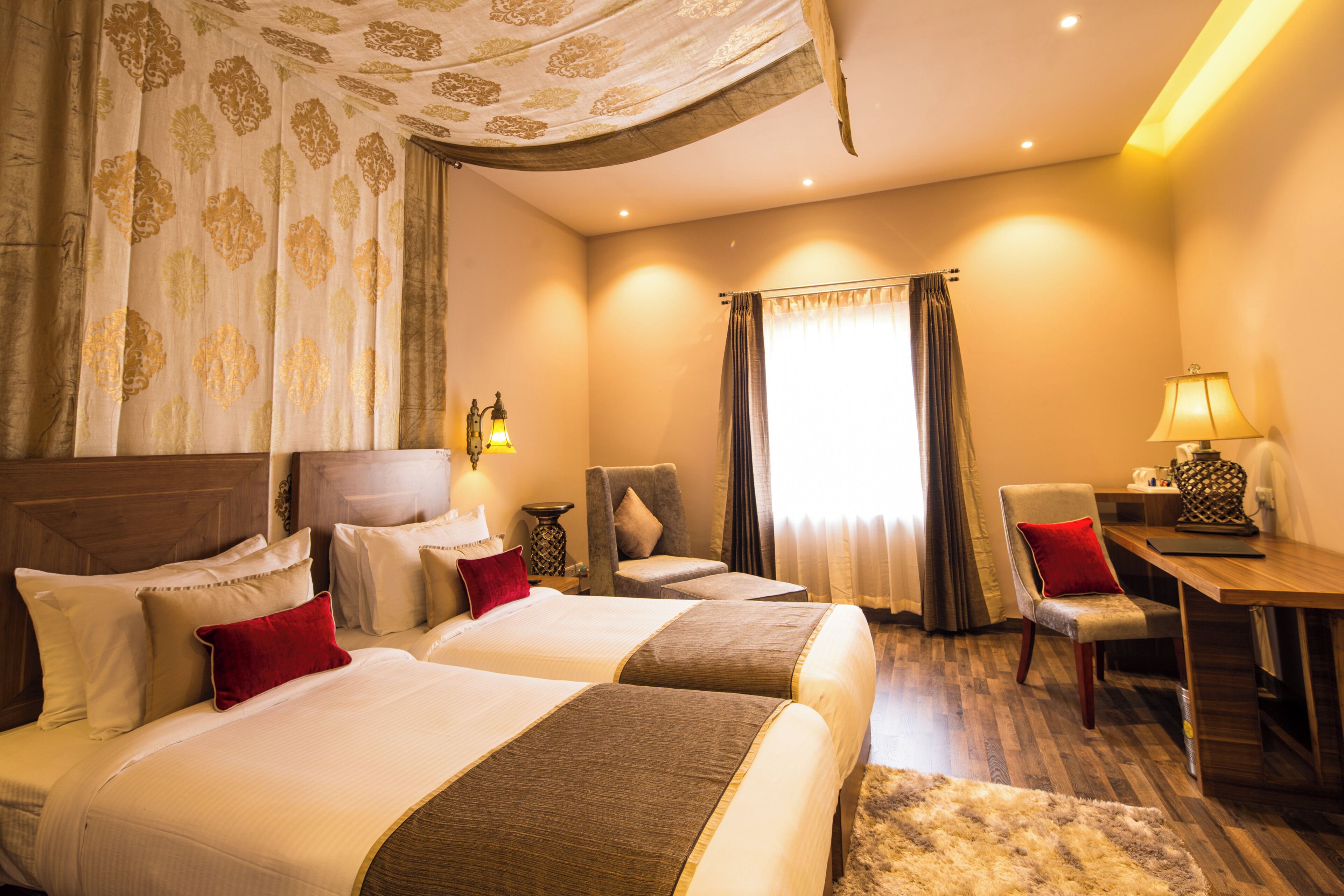 Une chambre d’hôtel avec deux lits, un bureau, une chaise et une lampe.