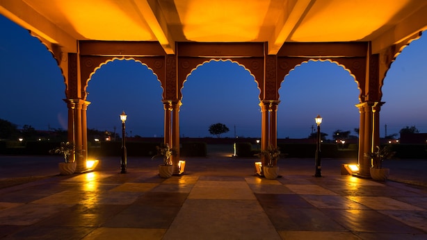 A covered outdoor area with arches and columns, illuminated by street lamps.