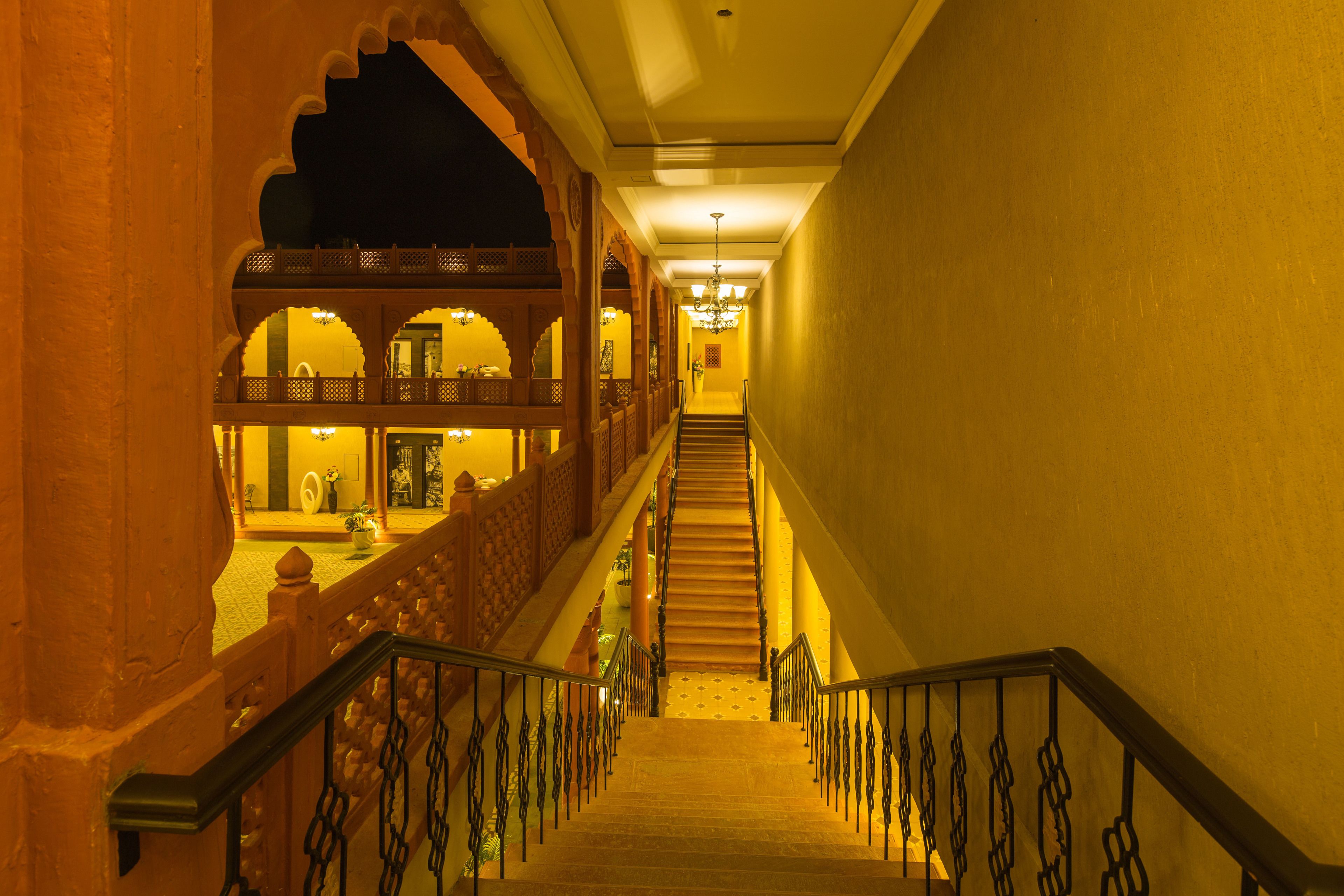 A grand staircase with ornate railings leading to a balcony with a view of the interior.