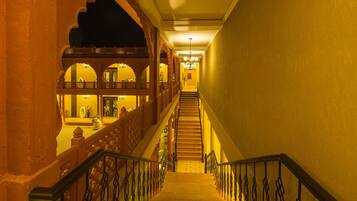 Una gran escalera con barandillas ornamentales que conduce a un balcón con vistas al interior.
