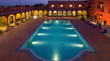 Relax by the pool surrounded by lush greenery and comfortable lounge chairs.