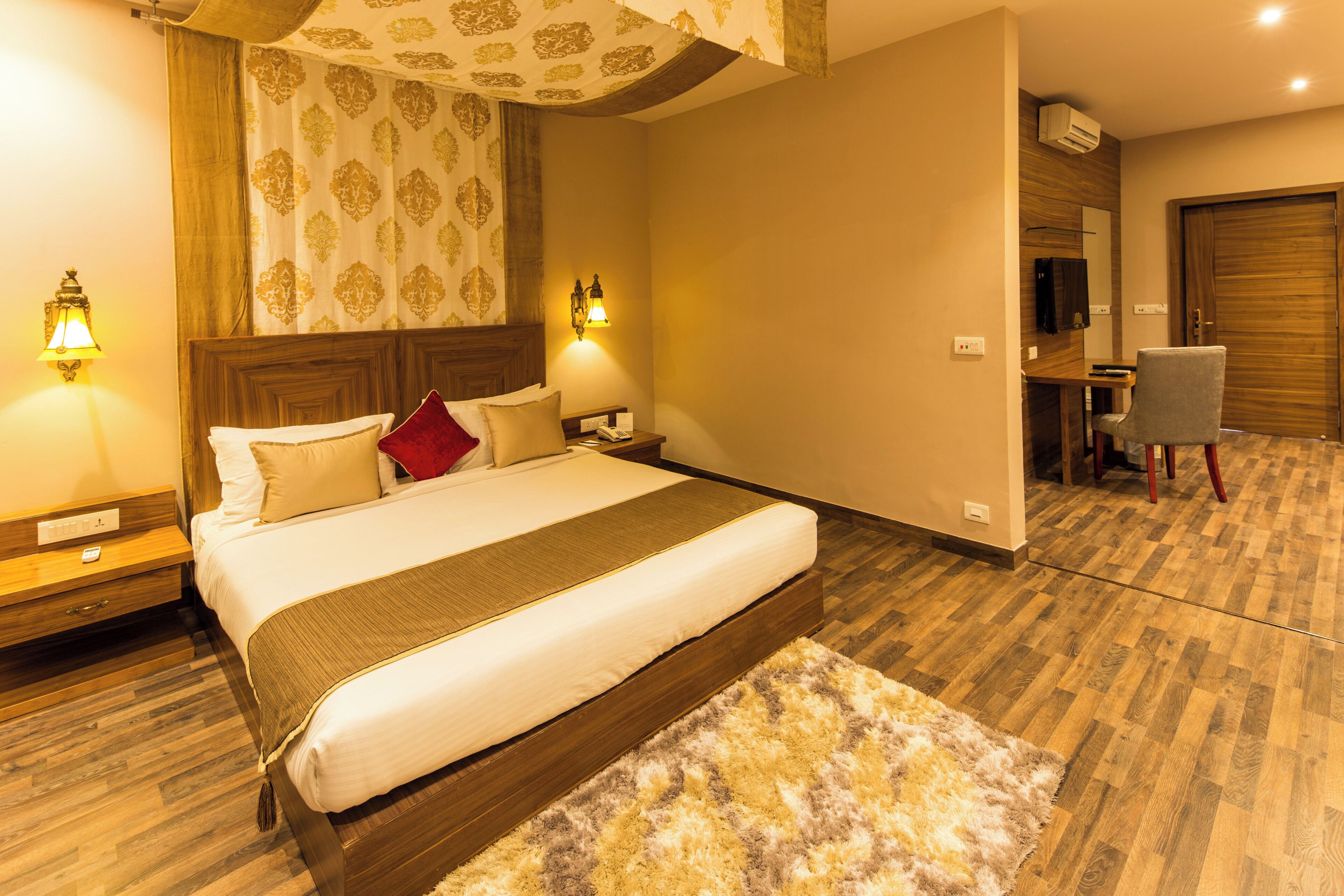 Une chambre d’hôtel avec un grand lit, deux lampes de chevet, un bureau avec une chaise et un plancher en bois.